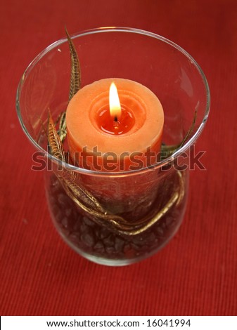 Decorative candle with gold leaf in a glass candle holder with stones.