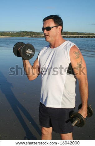 Man works out with weights on the beach just after sunrise.