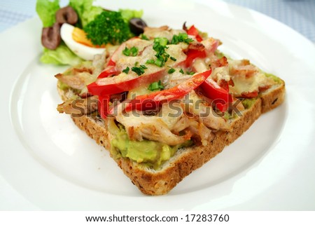 Grilled open chicken sandwich with avocado, peppers and cheese with a side salad.