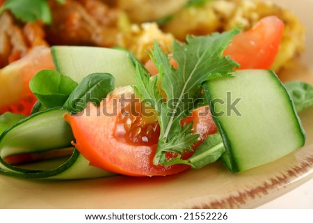 Small side salad of tomato, greens and shaved cucumber.