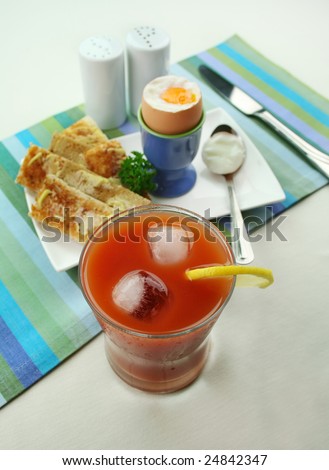 Breakfast of a boiled egg, toast fingers and fresh icy cold tomato juice.