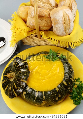 Classic pumpkin soup served in a Japanese pumpkin with bread rolls.