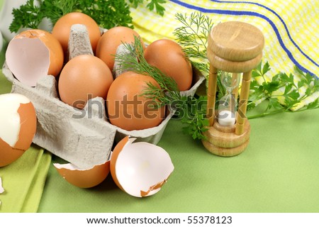 Egg timer with carton of boiled and cracked eggs with parsley.