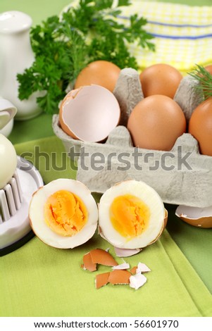 Freshly boiled egg in half along with a carton of brown eggs.