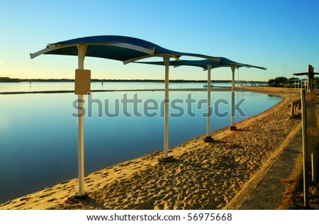 Shade sails on the beach by the lagoon at sunrise.