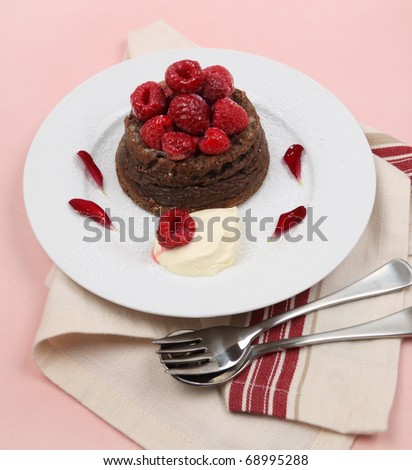 Delicious chocolate dessert topped with fresh raspberries and a dollop of cream.
