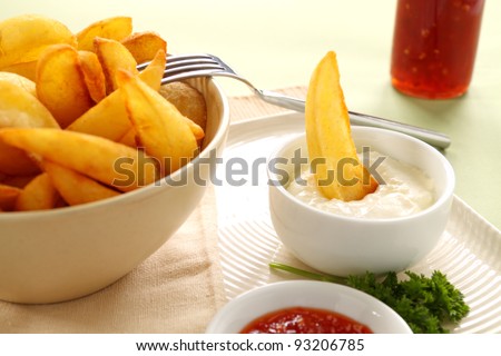 A crisp potato wedge dunked in a bowl of sour cream.