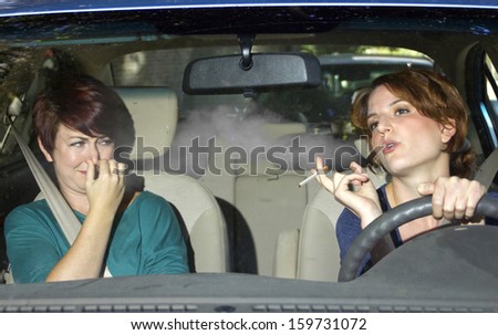 young female smoking while driving inside the car