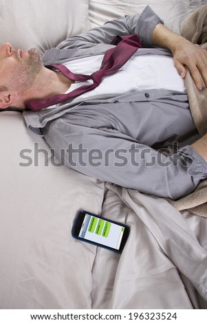 male sleeping in work clothes and receiving text messages from work