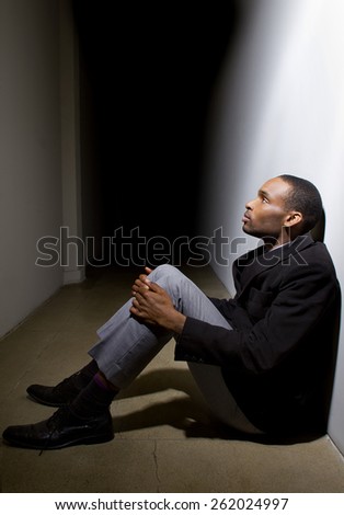 depressed man who lost faith sitting alone in a dark hallway