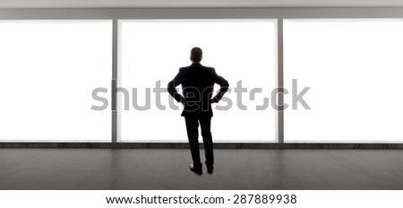 Middle aged businessman looking out a bright office window and thinking