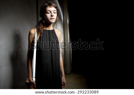 Young female walking lost and alone in a dark scary street alley.  She is suspicious someone is following her from the shadows.