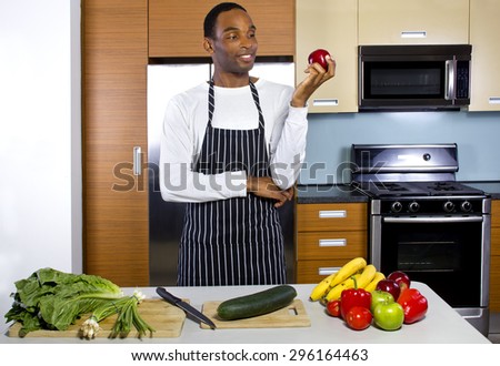 Young black man learning how to cook in a domestic kitchen with fruits and vegetables. He looks like a novice or amateur and trying to learn how to prepare healthy food.