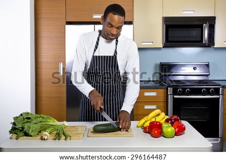 Young black man learning how to cook in a domestic kitchen with fruits and vegetables. He looks like a novice or amateur and trying to learn how to prepare healthy food.