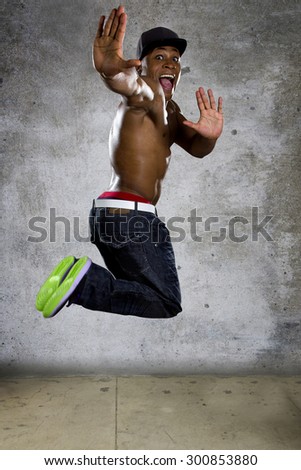 Healthy muscular black man jumping to show agility and energy.  The excited urban break dancer is on a grunge concrete background.