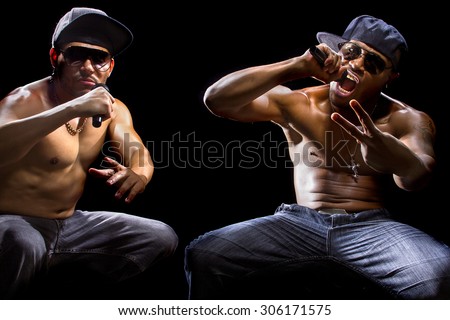 Rap concert with two muscular shirtless men with microphones.  The musicians are hip hop artists.
