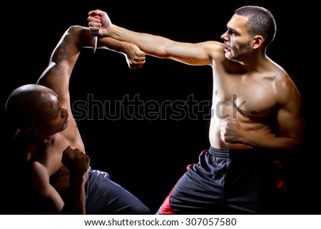Martial arts instructor demonstrating self defense against a knife attack. He is performing close quarter combat counter attacks against a weapon.
