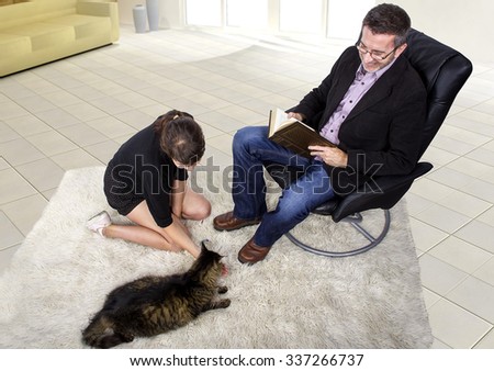 Family playing with a newly adopted pet cat at home.  The family is in a living room.