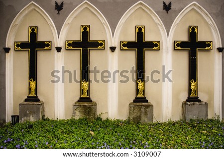 Four crosses and arches with some gold and plants in the forground, shot in Berlin on a spring day.