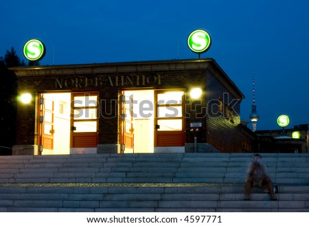 The S bahn station at Nord Berlin shot at night with a man sat on the steps reading a book.
