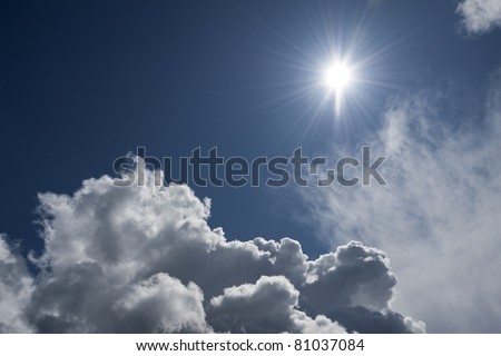 Bright sun with rays of light is shining over a big cloud