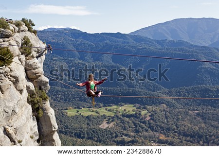 TAVERTET - NOVEMBER 16: Woman practicing highline in Spain on November 16, 2014. Highline is a balance sport that consists walking through a rope clamped between two points and great height below.