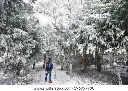 A man standing in front of snow covered trees.