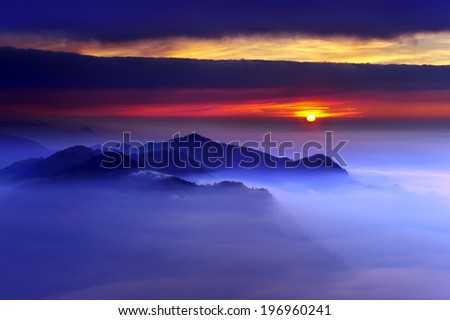 The sun setting behind a fog filled valley.