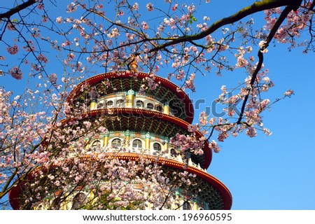 The top of a building seen through trees with pink blossoms.