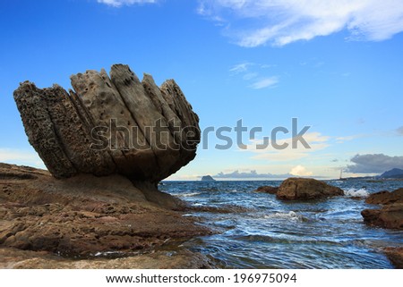 A large rock that is tilted sideways near a body of water.