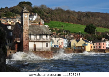 The old fishing village of Kingsand in Cornwall England where cottages are built on the edge of the sea. The village hall is built on the rocks and has a distinctive clock tower.