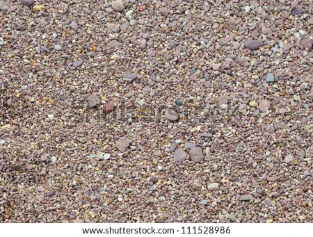 Coarse sand on a beach on the south coast of Cornwall England. The rocks and sand in this area is a light red or pink color.