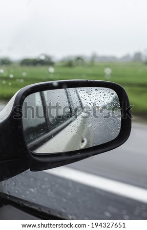 Traveling on a rainy day. Highway reflection in a car mirror.
