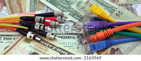 Fiber optic cables facing Cat 5 network cables over various denominations of currency