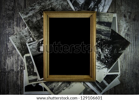 Photo frame with lots of photos lying on an old table.