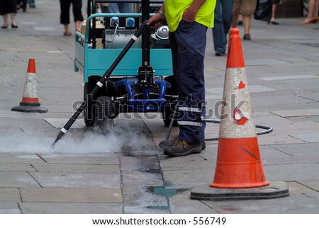 Steam cleaning pavement sidewalk of gum spewed out by yobs