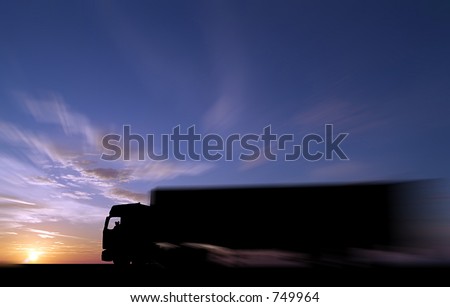 Silhouette of articulated freight vehicle against dramatic sunset or sunrise, with partial deliberate zoom blur