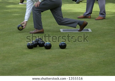 Man bowling a wood during traditional outdoor bowls match in England.