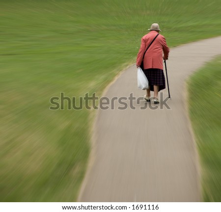 Zoom in to elderly female with walking stick on deserted, winding path. Plenty of space to add text.