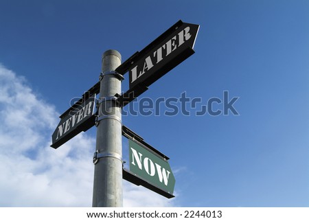 Low-angle of three-way finger signpost pointing to NOW, LATER and NEVER in stencil typeface, against blue sky with some cloud. Copyspace
