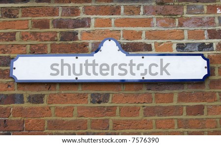 Blank street name sign fixed to red brick wall. Add your own text. Copyspace.