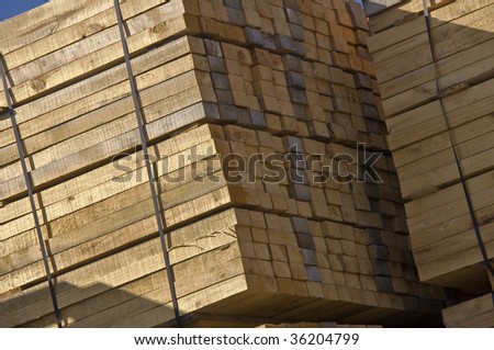 Diagonal low-angle view of rough timber plank stockpile