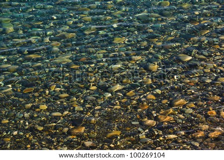 Natural ripple and rainbow effect on a beach of stones and pebbles photographed through shallow water close to the shore at Annalong, County Down, Northern Ireland.