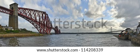 The original Forth Rail Bridge and the newer Forth Road Bridge stretch side by side from the harbor at North Queensferry across the waters of the Firth of Forth towards Edinburgh.