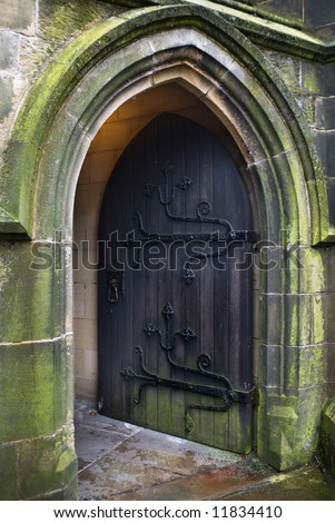Gothic style church doorway with old iron-hinged door standing open to welcome worshippers
