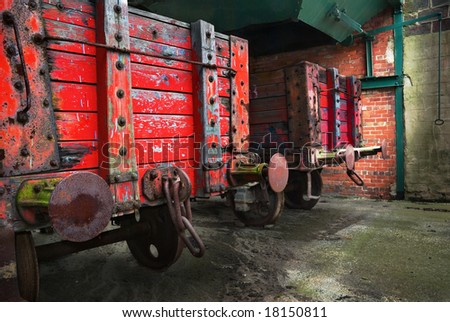 Vintage railroad wagons with peeling paint and rusty grunge texture, waiting to be filled from an overhead coal hopper