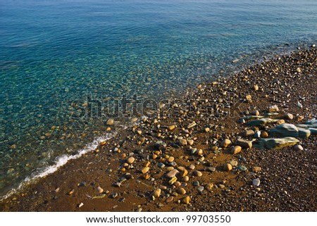 Annalong, County Down, Northern Ireland, where a sloping beach of stones and shingle is lapped by the sparkling transparent waters of the clear blue Irish Sea.