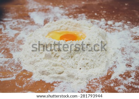 Making bread, mixing food ingredients: egg yolk on a flour staple closeup. Retro colors. Grain added