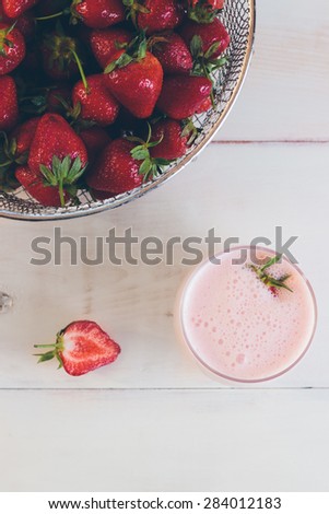 Fresh organic strawberries and strawberry milk shake on a white vintage wooden table