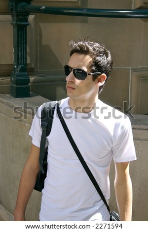 a young man walking through the city with shades